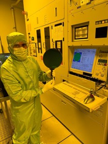 Muhammad N. Malik in a cleanroom gown holding a wafer with tweezers.